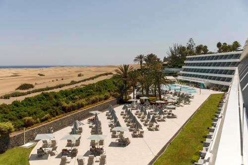 una fila de sillas y sombrillas junto a un edificio en Santa Monica Suites Hotel, en Playa del Inglés