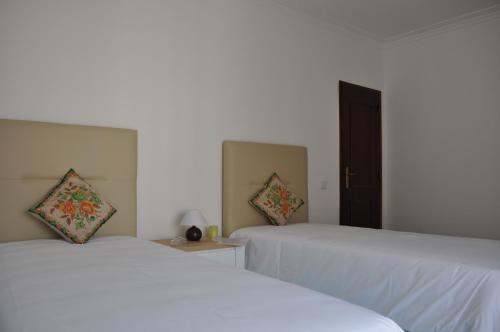 two beds in a room with white walls at Casa Manuela in Ericeira