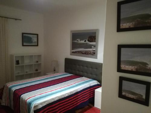 a bedroom with a bed and pictures on the wall at Casa do Mar - Nazaré in Nazaré