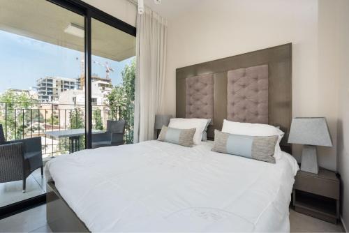 1 dormitorio con 1 cama blanca grande y balcón en Kerem Charm by Five Stay, en Tel Aviv