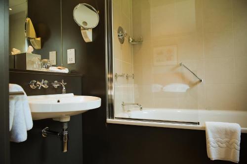 a bathroom with a sink and a tub and a mirror at Hart's Hotel in Nottingham