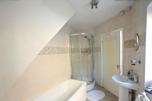 a bathroom with a shower and a sink and a tub at East End London Garden Flat in London