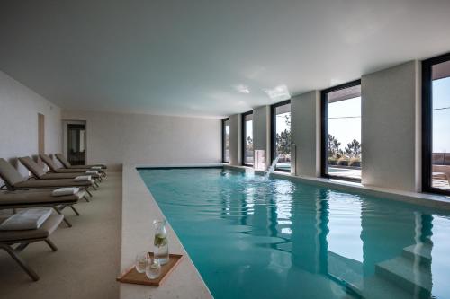 a swimming pool in a building with windows at Casa de São Lourenço - Burel Panorama Hotel - member of Design Hotels in Manteigas