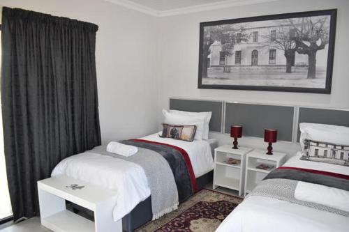 a bedroom with two beds and a picture on the wall at Middelplaas Paarl Guesthouse in Paarl