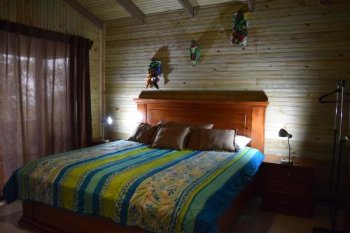 a bedroom with a bed with a wooden wall at Mirador Valle del General in La Ese