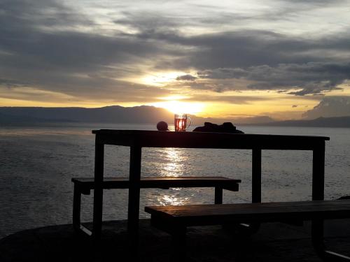a table with a cat sitting on it with the sunset at Pondok Berata Dapdap in Balige