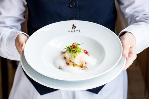 a man holding a white plate with food on it at Hart's Hotel in Nottingham
