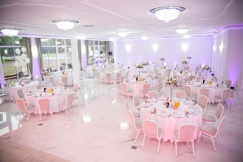 a room with white tables and chairs and purple lighting at Hotel Greys Polonia in Zasutowo