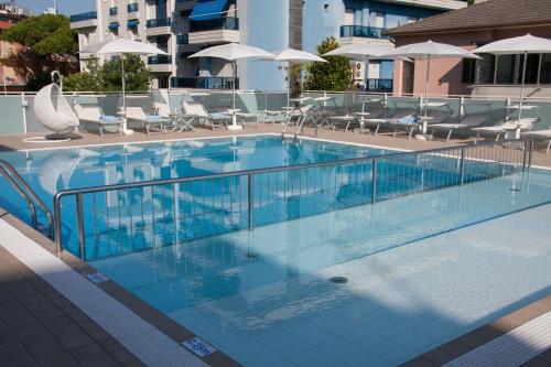 a swimming pool with chairs and umbrellas on a building at Hotel Albatros 3 Stelle Superior in Lido di Jesolo