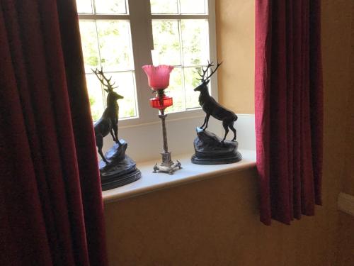a window sill with two statues of a deer and a candle at Hundalee House in Jedburgh