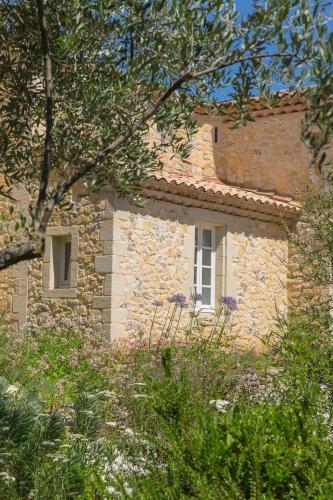 a stone building with two windows and trees at Le Mas des Alexandrins in Uzès