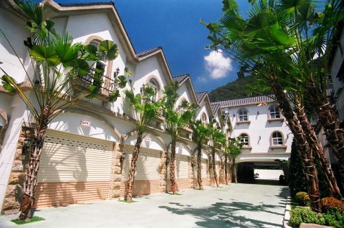 a row of palm trees in front of a building at 意大利商務溫泉汽車旅館 in Jiaoxi