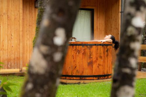 a woman is sitting in a wooden bath tub at La Escondida Pucon in Pucón
