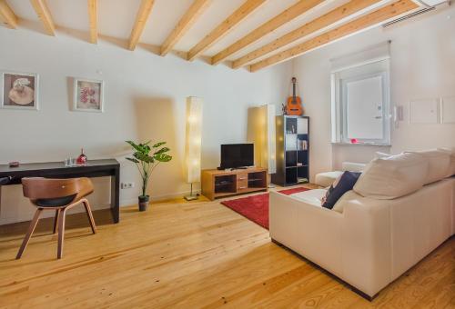 ein Wohnzimmer mit einem weißen Sofa und einem TV in der Unterkunft Graça Cozy Duplex in Lissabon