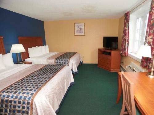 a hotel room with two beds and a television at Swiss Chalets Village Inn in North Conway