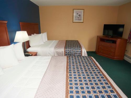 a hotel room with two beds and a flat screen tv at Swiss Chalets Village Inn in North Conway