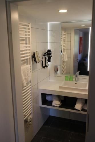 a bathroom with a sink and a mirror at Logis Hôtel Restaurant Au Lion Rouge in Bartenheim
