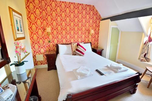 a bedroom with a bed with a red wall at The Angel Hotel in Coleford