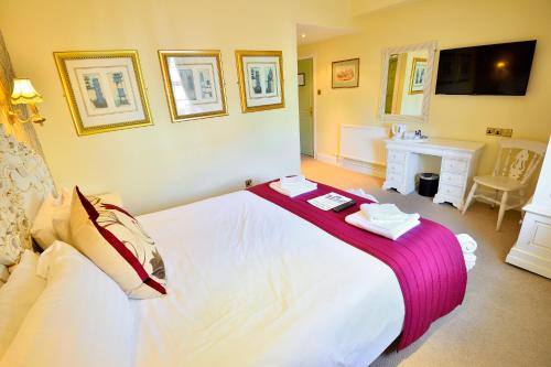 a bedroom with a large white bed and a desk at The Angel Hotel in Coleford