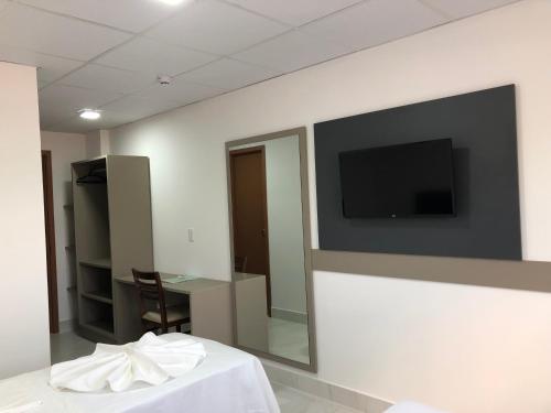 a room with a tv on a wall with a table at Hotel Oásis de Patos in Patos