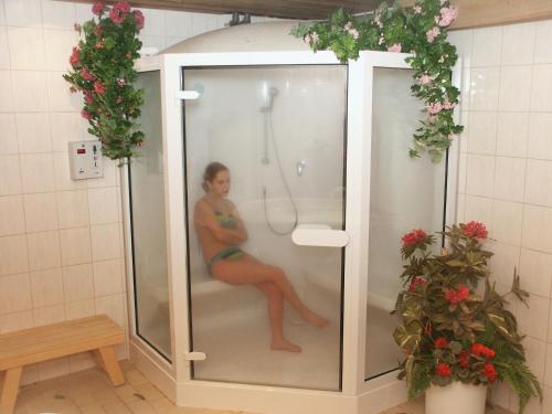 a woman sitting in a shower in a bathroom at Hotel Mühlenberg in Bad Sachsa
