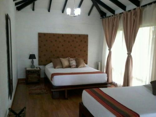 a bedroom with two beds and a large window at Hotel Tata Premium in Pueblo Tapao