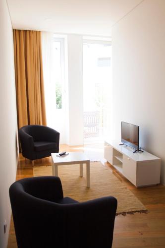 a living room with two chairs and a television at Banho de Mar in Póvoa de Varzim