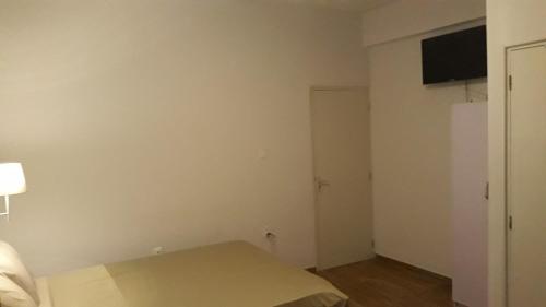 a small bedroom with a bed and a television at Waterland Suites in Paramaribo