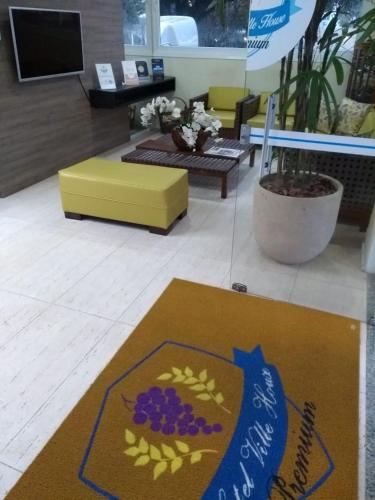 a living room with a yellow couch and a rug at Hotel Ville House Premium in Canoas