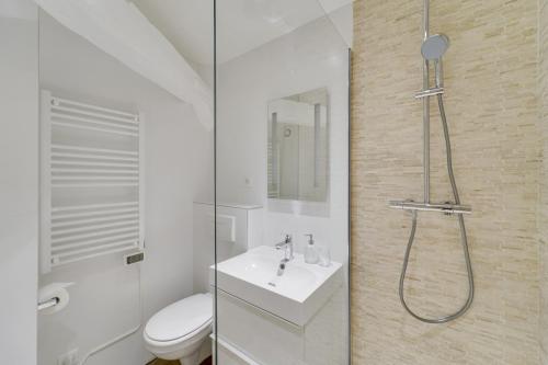 a white bathroom with a shower and a sink at Les Mansardes du Roi in Versailles