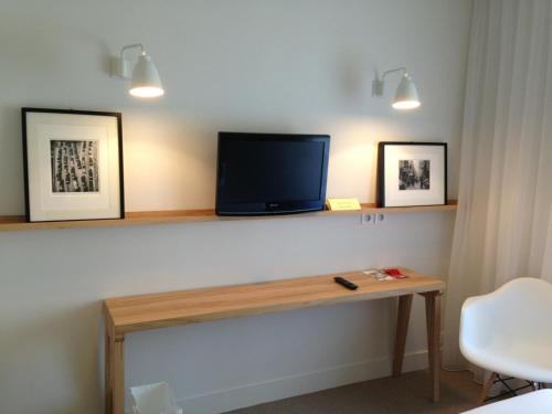 a room with a desk with a tv on a wall at Hôtel et Apparts Marin in Laval