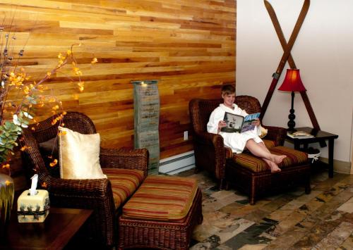 a woman sitting in two chairs reading a book at Vail Racquet Club Mountain Resort in Vail
