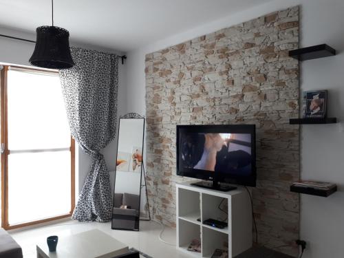 グダニスクにあるNew flat near seaのレンガの壁、テレビ付きのリビングルーム