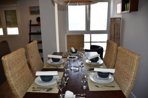 uma mesa de jantar com cadeiras e um conjunto de mesa com pratos em Sweet Velázquez Apto. zona Playa Victoria em Cádiz