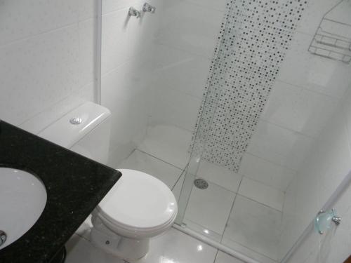 a white bathroom with a shower and a toilet at Kitnets & Flats in Ubatuba