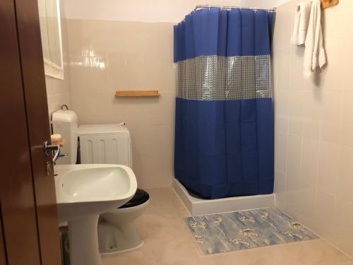 a bathroom with a toilet and a blue shower curtain at Casa da Igreja in Santana