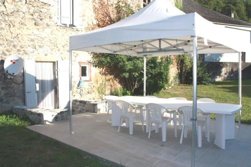 a white table and chairs under a white umbrella at Gîte XIIIème siècle - 3 étoiles - WIFI - Salle de sport in Osse-en-Aspe