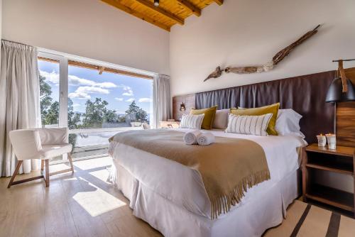 Aguila Mora Suites & Spa في سان كارلوس دي باريلوتشي: غرفة نوم بسرير كبير ونافذة كبيرة