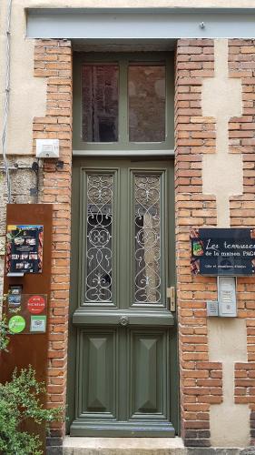 ヴィルフランシュ・ド・ルエルグにあるGITE PAGO DUPLEXの煉瓦造りの建物側の緑の扉