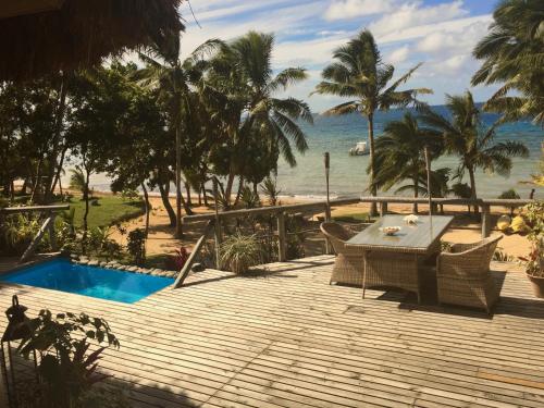 a wooden deck with a table and chairs next to the beach at Oneta Resort in Ono Island