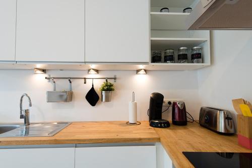 eine Küche mit weißen Schränken und einer Arbeitsplatte aus Holz in der Unterkunft La petite Naimette in Lüttich