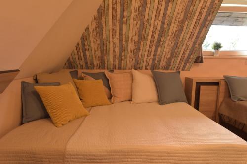 a bed with yellow and gray pillows and a window at Apartment Sofia-Konaci in Kopaonik