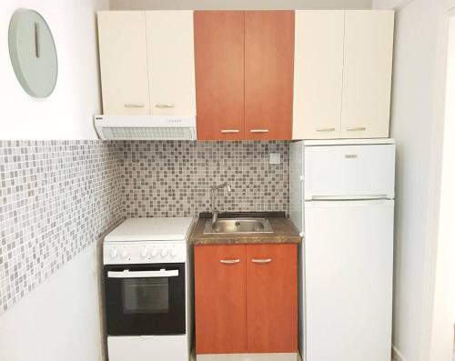 a small kitchen with white appliances and brown cabinets at Central Park Kallikrátia in Nea Kalikratia