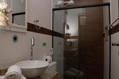 uma casa de banho com um lavatório e uma cabina de duche em vidro. em Pousada Encantos do Peró em Cabo Frio