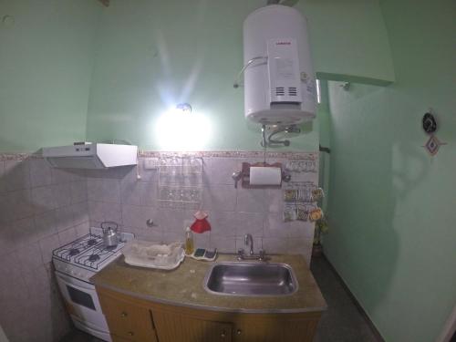 Il comprend une cuisine avec un évier, une cuisinière et une lampe. dans l'établissement Departamentos Chacabuco Familiar, à Colón