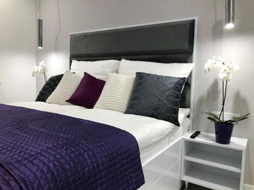 a bedroom with a large bed with purple sheets and pillows at Luxury Apartment - 3 lakes in Katowice