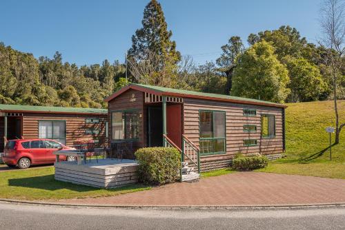 a small cabin with a car parked in front of it at Blue Lake TOP 10 Holiday Park in Rotorua