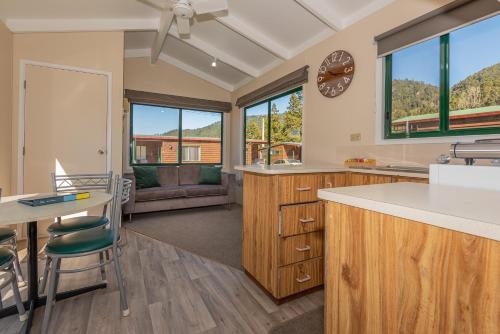 a kitchen with wooden cabinets and a clock on the wall at Blue Lake TOP 10 Holiday Park in Rotorua