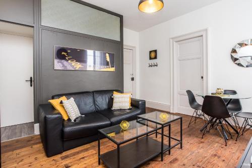 a living room with a black leather couch and a table at Appartements Scaliger Wifi Proche Gare in Agen