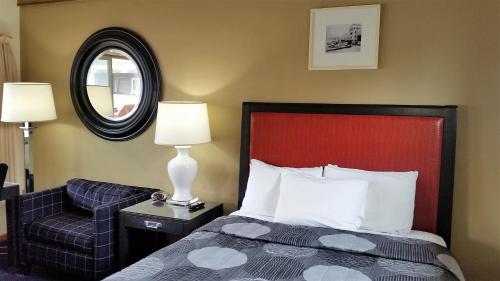 um quarto com uma cama, uma cadeira e um espelho em The Simplicity Inn em Marshfield